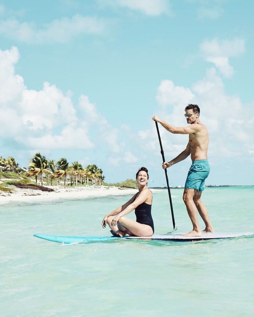 couple paddle surfing on the beaches of long bay beach club